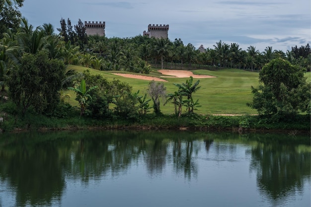 Malerische Aussicht schöner Golfplatz Teich Schloss Hintergrundansicht grüner Rasen Wald Reflexion Bäume Busch üppig im Wasser Landschaft Tal See Landschaftspark