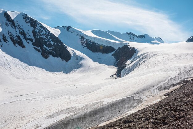 Malerische Berglandschaft mit großem Gletscher im Sonnenlicht Ehrfürchtige verschneite Landschaft mit Gletscherzunge unter Zirruswolken Wunderschöner Alpenblick auf schneebedeckte Berggipfel in sehr großer Höhe an sonnigen Tagen