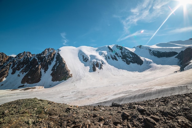 Malerische Berglandschaft mit großem Gletscher im Sonnenlicht. Fantastische Landschaft mit Gletscherzunge unter der Sonne am blauen Himmel. Wunderschöner Alpenblick auf schneebedeckte Berggipfel in sehr großer Höhe an sonnigen Tagen