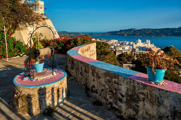 Malerische malerische Aussicht auf die griechische Stadt Plaka auf der Insel Milos über rote Geranienblumen