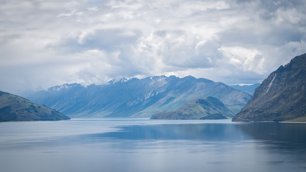 Malerischer Alpensee, umgeben von Bergen, die an einem sonnigen Tag aufgenommen wurden, ist der Lake Hawea, Neuseeland