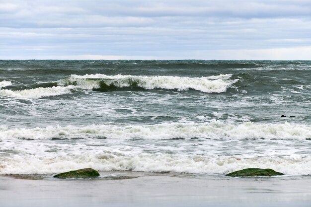 Malerischer Blick auf das blaue Meer mit sprudelnden und schäumenden Wellen und schönem bewölktem Himmel