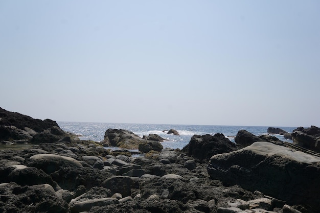 malerischer Blick auf das Meer vor Felsen vor klarem Himmel an einem sonnigen Tag