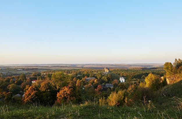 Malerischer Blick auf den Inselberg Pidkamin auf dem angrenzenden Hügel und dem nahe gelegenen Dorf in der Region Brody in Galychyna, Ukraine