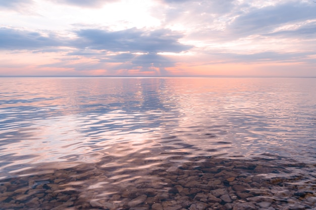 Malerischer Blick auf einen wunderschönen Sonnenuntergang über einem Fluss an einem Frühlingsabend mit bewölktem Himmel