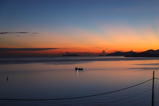 Malerischer blick von der silhouette des fischerbootes im ruhigen ozean bei sonnenaufgang