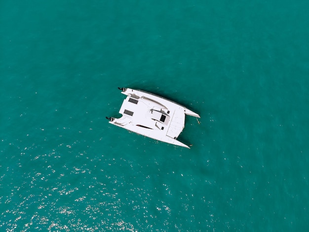 Malerischer Blick von oben auf einen riesigen weißen Katamaran, der über die Tiefsee segelt. Luftaufnahme.