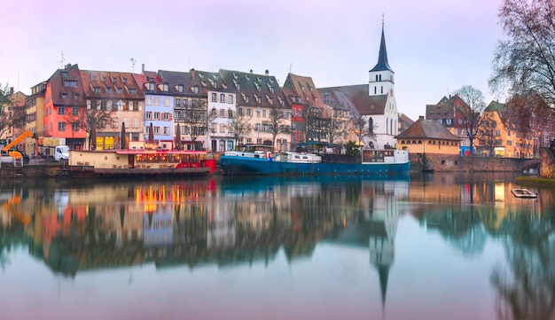 Malerischer Quai des Pecheurs, Fisherman Wharf und evangelische Kirche Saint Guillaume mit Spiegelreflexionen im Fluss Ile während der blauen Morgenstunde, Straßburg, Elsass, Frankreich