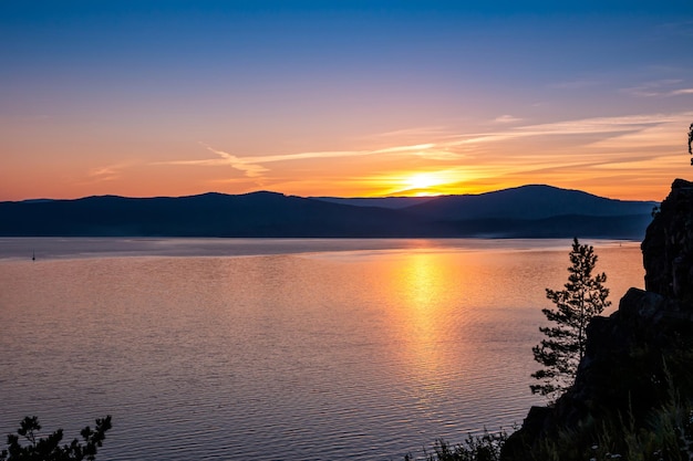 Malerischer See und felsiges Ufer nach Sonnenuntergang