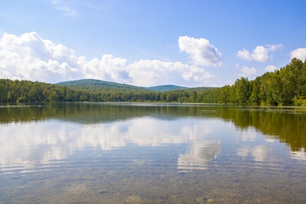 Malerischer See zwischen Bergen und Wald an einem Sommertag