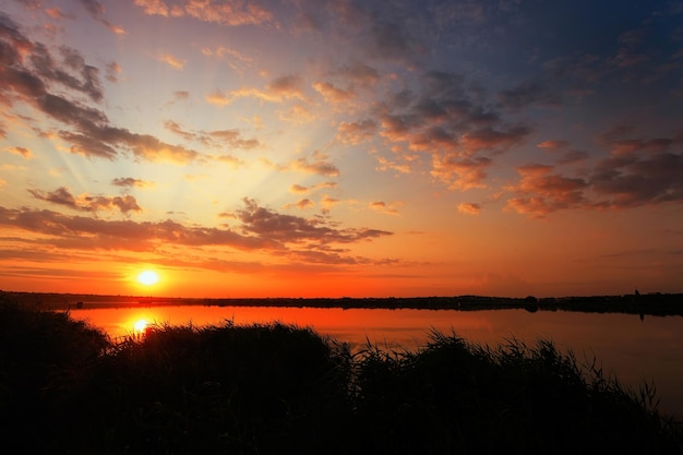 Malerischer Sonnenaufgang über dem See mit Wolken und Sonnenstrahl