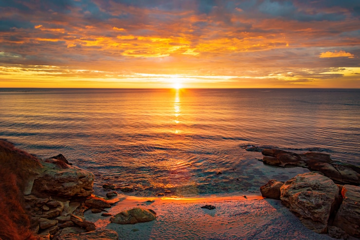 Foto malerischer sonnenaufgang über einem felsigen strand.