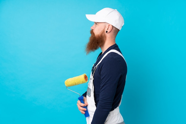 Malermann mit langem Bart über der lokalisierten blauen Wand, die Seite schaut