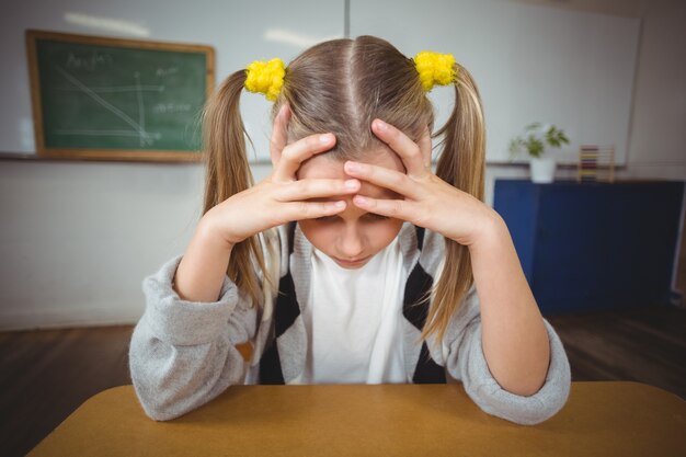 Malestar alumno sentado en su escritorio en un aula