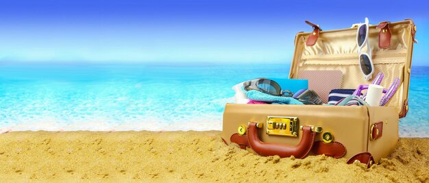 Maleta abierta completa en banner de fondo de playa tropical