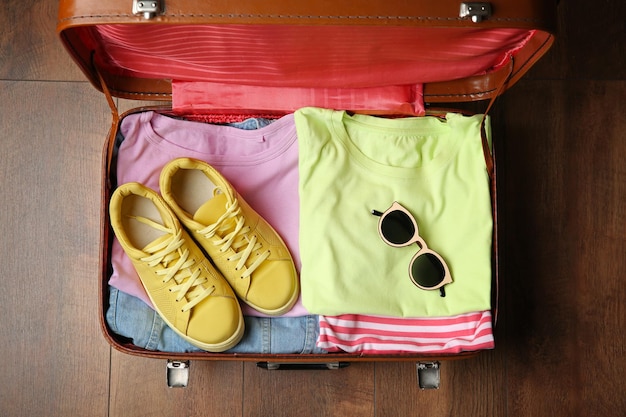 Foto maleta abierta con ropa en piso de madera