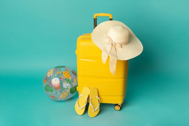 Maleta amarilla con chanclas y sombrero sobre fondo azul Concepto de viaje Estilo minimalista
