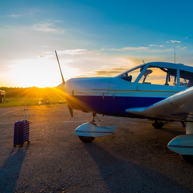 Foto una maleta azul y un pequeño jet privado estacionado