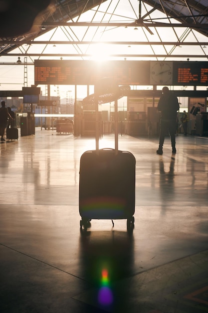 Maleta frente a un tablero de destino en una estación al atardecer