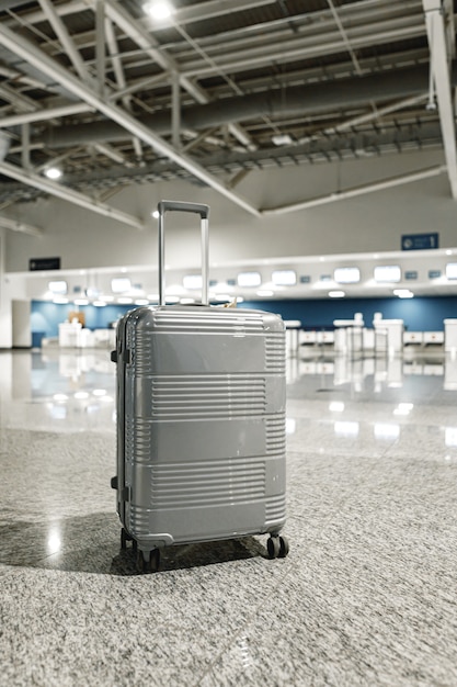 Foto maleta de viaje gris en el pasillo del aeropuerto vacío