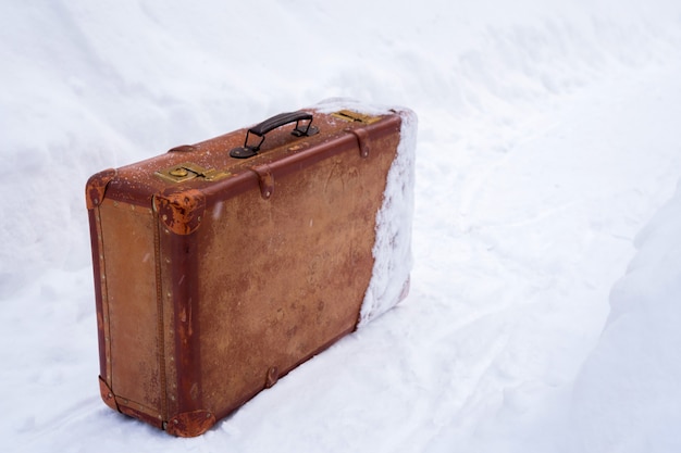 Foto maleta vieja de cuero marrón en la nieve