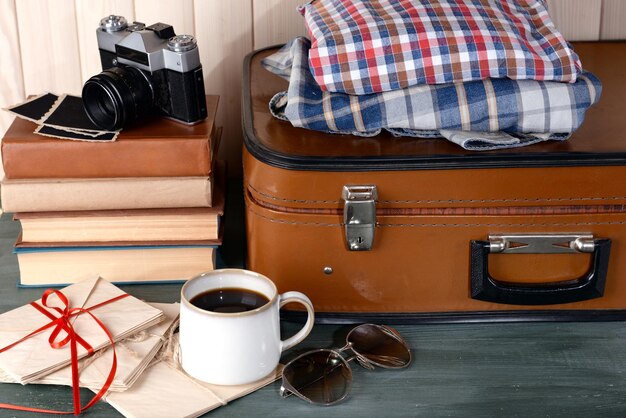 Maleta vintage con ropa y libros sobre fondo de madera