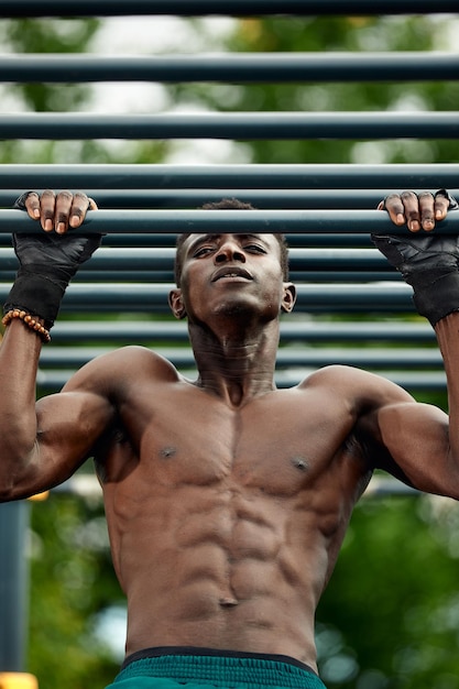 Malhar pela manhã Jovem africano forte em roupas esportivas se exercitando ao ar livre Conceito de treinamento esportivo Estilo de vida ativo saudável TRX