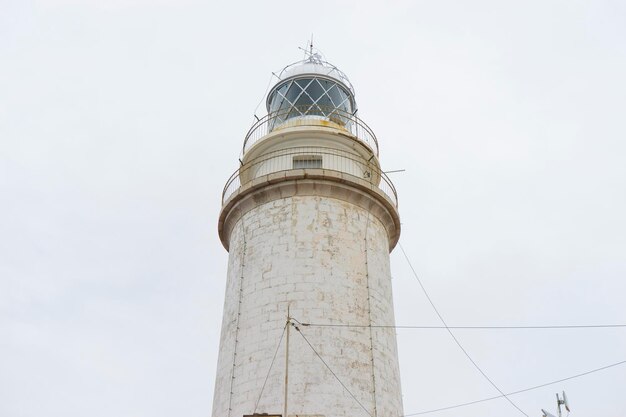 Mallorca, Leuchtturm neben dem Mittelmeer, blauer Himmel ohne Wolken mit ruhigem Wasser. dient dazu, Schiffe vor Felsen zu warnen