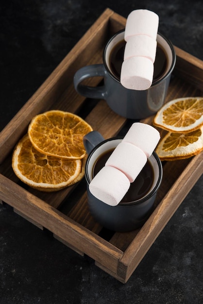 Malvavisco con café en una taza con rodajas de naranja secas en un plato de madera para cortar