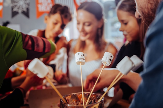 Malvavisco con caras. Cerca de malvaviscos en palos de madera con caras divertidas en celebración de Halloween