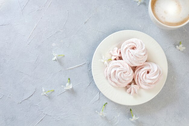 Malvaviscos caseros en un plato con una taza de café recién hecho decorado con flores.