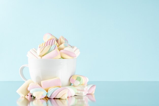 Malvaviscos coloridos caramelos masticables en una taza en azul.