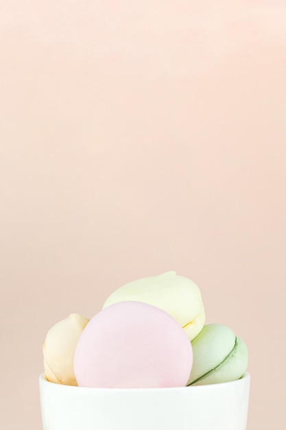 Los malvaviscos dulces y coloridos parecen macarrones franceses en taza de café blanca de porcelana Espacio libre para texto