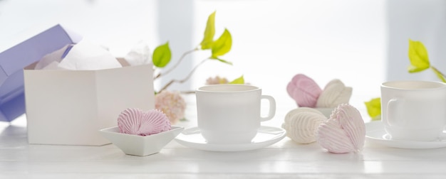 Malvaviscos en forma de corazón de color rosa y blanco y tazas con té Dulces artesanales del desierto con composición romántica de bebidas para el día de San Valentín