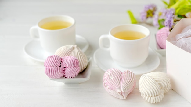 Malvaviscos en forma de corazón y tazas con composición romántica de té Dulces artesanales del desierto con bebida