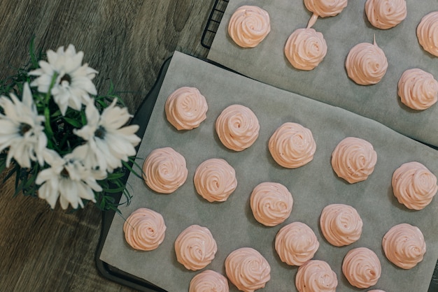 Malvaviscos rosas caseros sobre papel de hornear en la cocina.