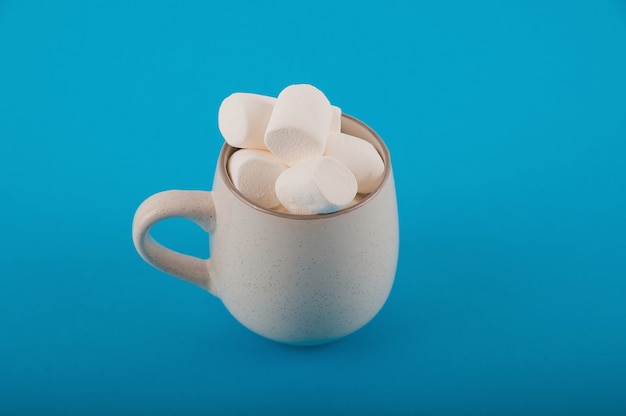 Foto malvaviscos en una taza en un espacio azul de cerca y copie el espacio. marshmallow en una vista superior del patrón de taza en un espacio azul.