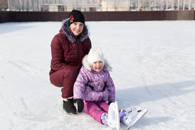 Mamá abraza a su hermosa hija en el invierno en la pista.