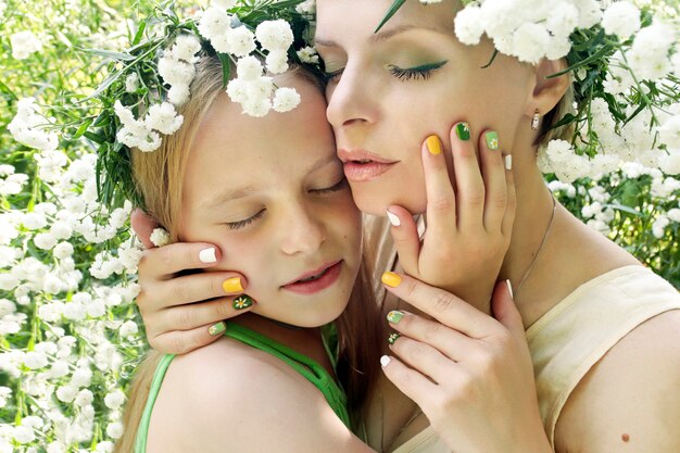 Mamá abraza a su hija contra la configuración de flores en verano