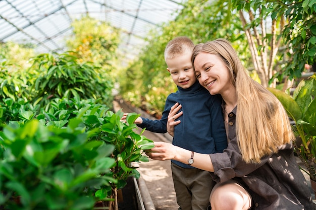 Mamá abraza a su hijo en un invernadero con plantas.