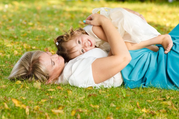 Mamá abrazó a su pequeña hija en el parque en verano en un clima soleado