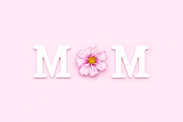 Mama. Abstrakte Textliebeserklärung aus weißen Buchstaben und Blumen auf rosa Hintergrund. Kreatives Konzept Muttertag, Grußkarte, Postkarte. Ansicht von oben Flach liegend