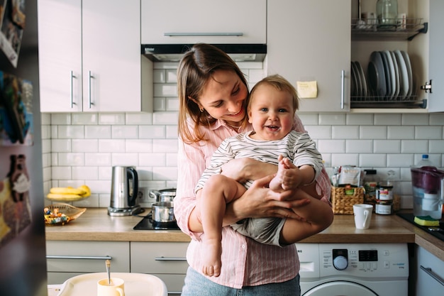 Mamá alimenta a un niño pequeño en casa con yogur de un concepto familiar de cuchara