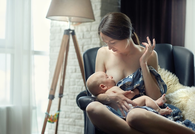 Mamá amamantando al niño por la tarde sentado en una silla