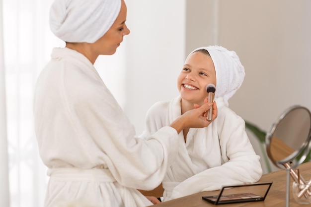 Mamá amorosa haciendo el primer maquillaje a su linda hijita en casa