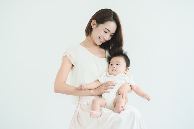 Mamá asiática sosteniendo a un bebé en la habitación luminosa