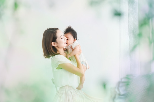 Mamá asiática sosteniendo a un bebé en la habitación luminosa