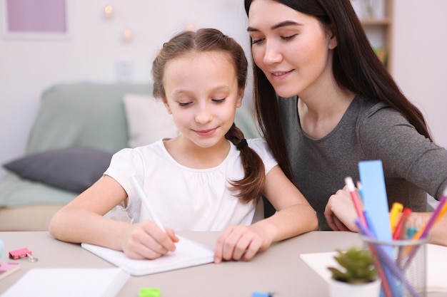 Mamá ayuda a la niña a hacer la tarea de los niños y los padres.