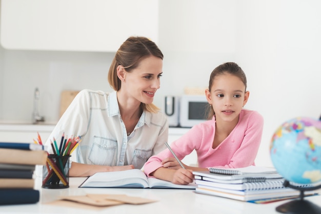 Mamá ayuda a su hija a hacer su tarea en la cocina.