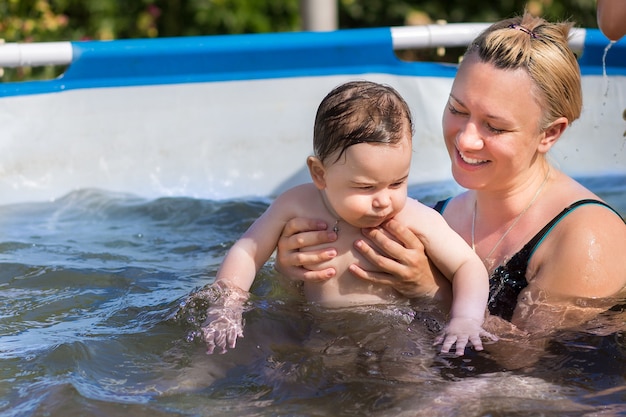 Foto mamá con bebé divirtiéndose en la piscina.